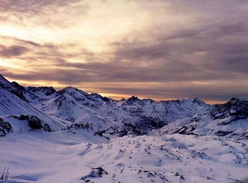 Scenic view of snow covered mountains against cloudy sky