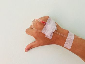 Cropped hand of patient with iv drip over white background