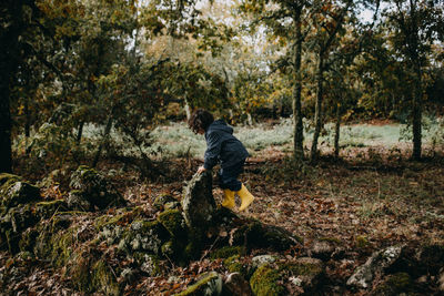 Girl with yellow rubber boots playing in the woods