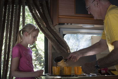 Grandfather serving coffee in cup by daughter in motor home