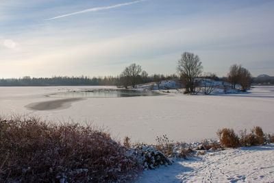 Scenic view of frozen field against sky during winter