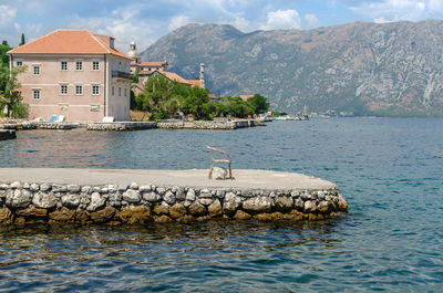 Old rusty chair on a sea dock, sea and coastal houses