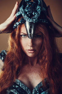 Portrait of young woman holding crown against colored background