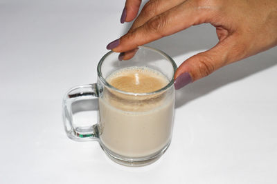 Close-up of hand holding glass over white background