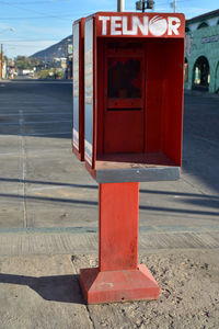 Red telephone booth against sky