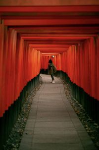 Rear view of woman walking on footpath amidst buildings