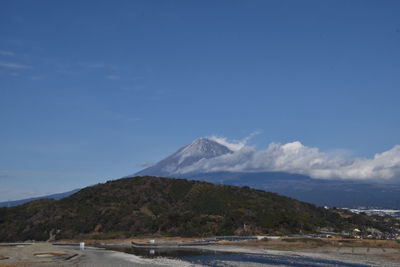 Scenic view of sea and mountains against blue sky