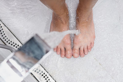Woman washing feet, close up. female stands under shower water.