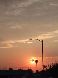 Silhouette street light against orange sky