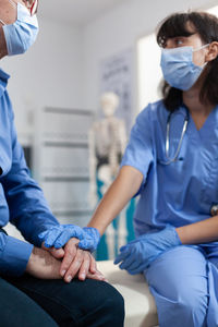 Nurse wearing mask consoling patient at clinic