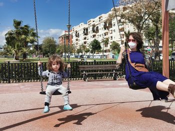 Mother and daughter at the park playing on swing .