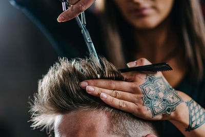 Hairdresser cutting man hair at salon