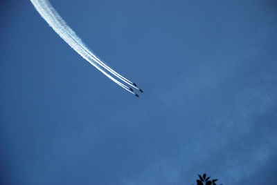 Low angle view of airplane flying against blue sky