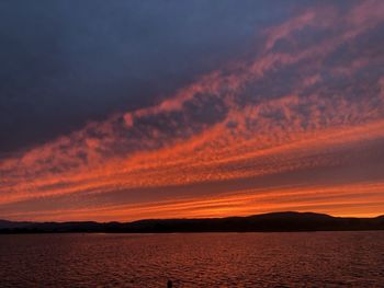 Scenic view of sea against dramatic sky during sunset