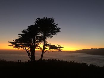 Silhouette tree by sea against sky during sunset