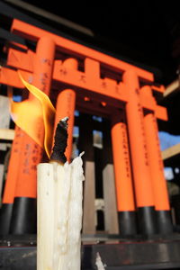 Close-up of lit candle against torii gate