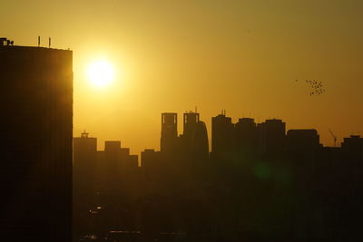Silhouette buildings against sky during sunset