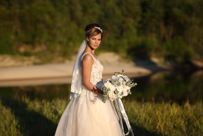 Bride with a bouquet of flowers on the background of the river