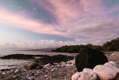 Rocks on beach against sky during sunset