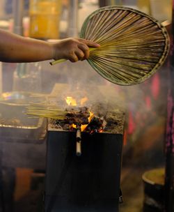 Midsection of person holding candles on barbecue grill