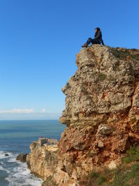 Person on rock against sky