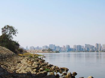 Scenic view of river by buildings against clear sky