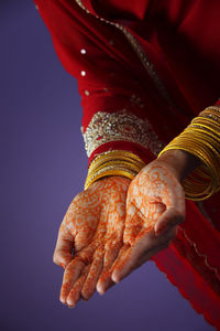 Midsection of woman showing henna tattoo against colored background
