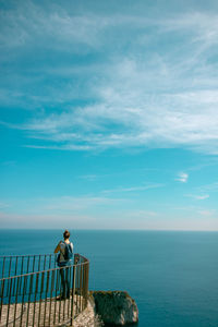 Woman standing at observation point by sea against sky
