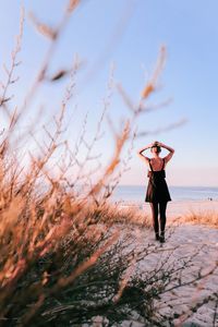 Rear view of woman standing at beach