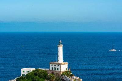 Lighthouse by sea against sky