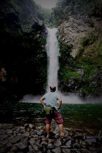 Rear view of man standing against waterfall