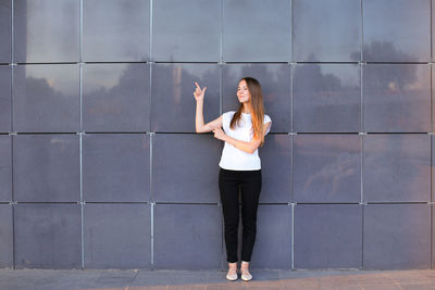 Full length of woman standing against wall