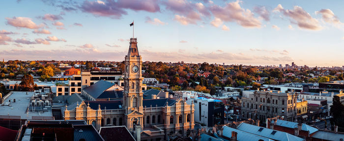 Panoramic shot of clock tower in town against sky during sunset