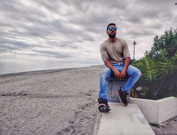 Full length of young man sitting against sky