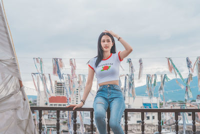 Young woman sitting on railing against city