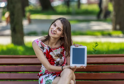 Portrait of woman sitting on bench in park