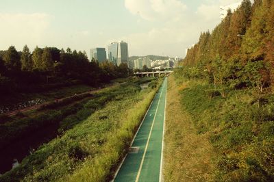 Road leading towards city against sky
