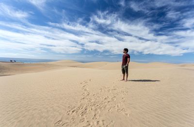 Rear view of man standing on sand at beach