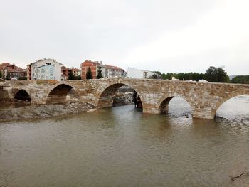 Bridge over river in city against clear sky