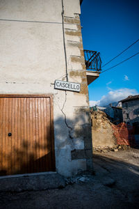 Text on wall by building against blue sky