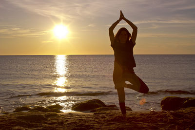Man standing on beach against sky during sunset