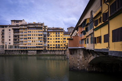 Buildings by river against sky