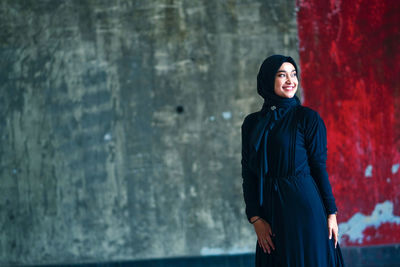 Beautiful indonesian woman wearing a black hijab against the rustic wall as a background