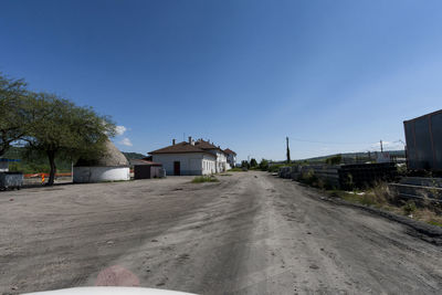 Road amidst buildings against blue sky