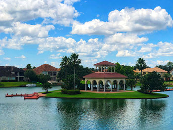House by lake and buildings against sky