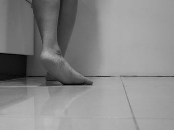 Low section of woman standing on tiled floor at home