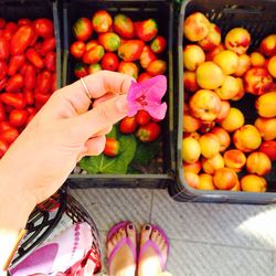 Low section of woman holding hydrangea over fruits and vegetables in crates at market