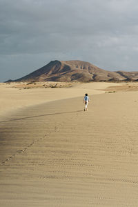 Man riding motorcycle on desert against sky