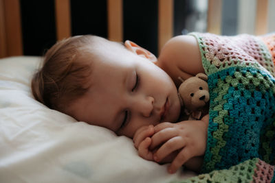 Close-up of baby sleeping on bed at home