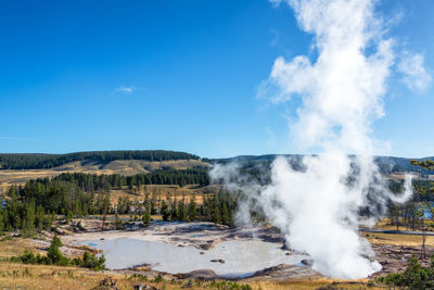 View of waterfall on landscape against blue sky